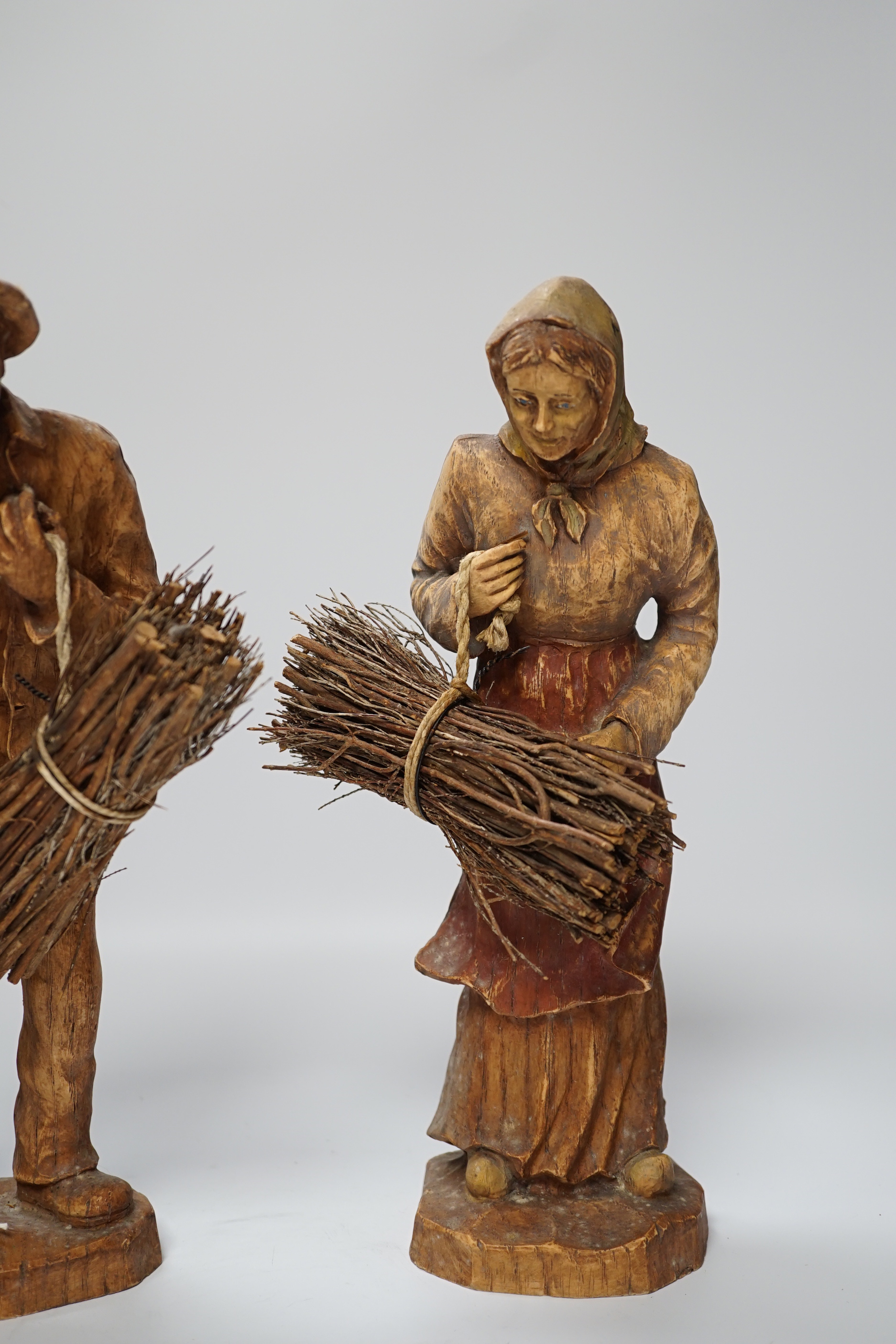 A pair of composition peasant figures gathering firewood, tallest 33cm